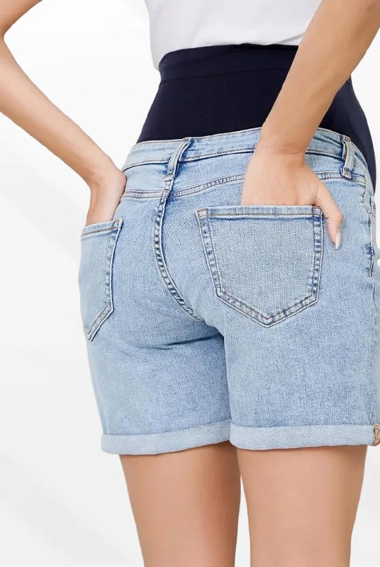Pregnancy Capri Jeans High Waist Tummy Control Rolled Cuff Denim Shorts worn by a pregnant woman with hands in back pockets, light blue denim with rolled cuffs.