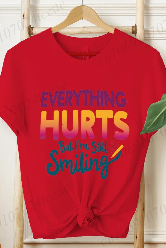Red short sleeve Everything Hurts But I'm Still Smiling design shirt with colorful text, casual summer fashion tee.