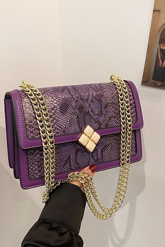 Luxury purple women's single shoulder bag with faux snake leather, gold chain strap, and decorative flower clasp.