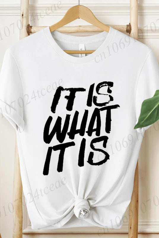 White women's T-shirt with IT IS WHAT IT IS graphic text, short sleeves, knotted at the front, from the IT IS WHAT IT IS