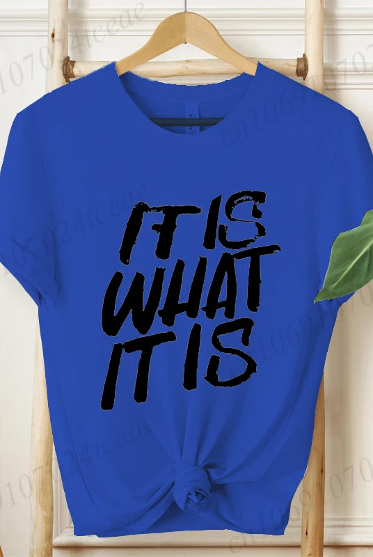 Blue women's IT IS WHAT IT IS graphic T-shirt with bold black text, short sleeves, knotted at the waist, casual summer
