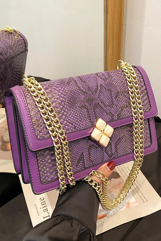 Luxury purple women's single shoulder bag with snake-patterned PU leather, gold chain strap, and floral clasp closure.