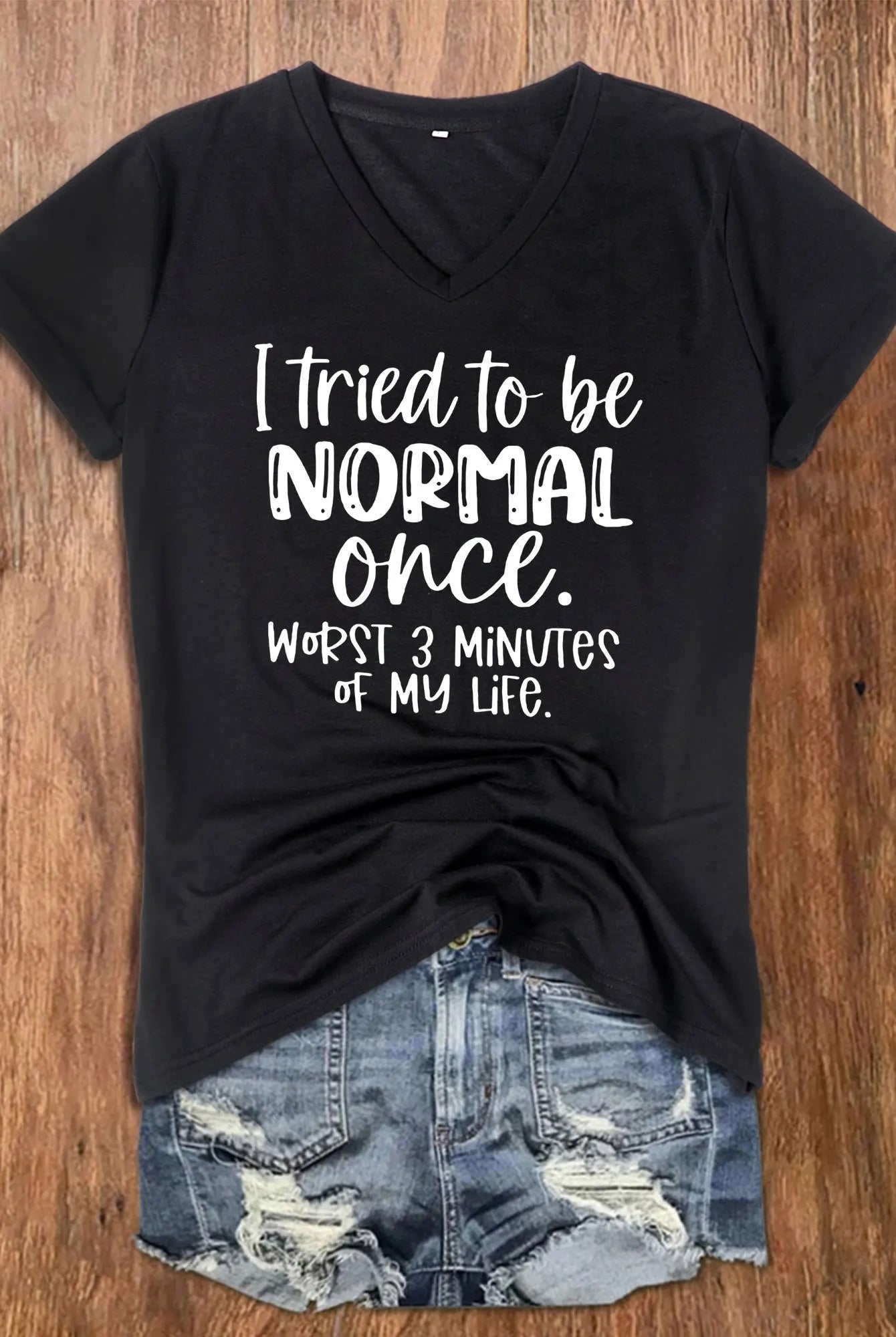 Black women's V-neck T-shirt with white text reading I Tried To Be Normal Once, paired with distressed denim shorts on a