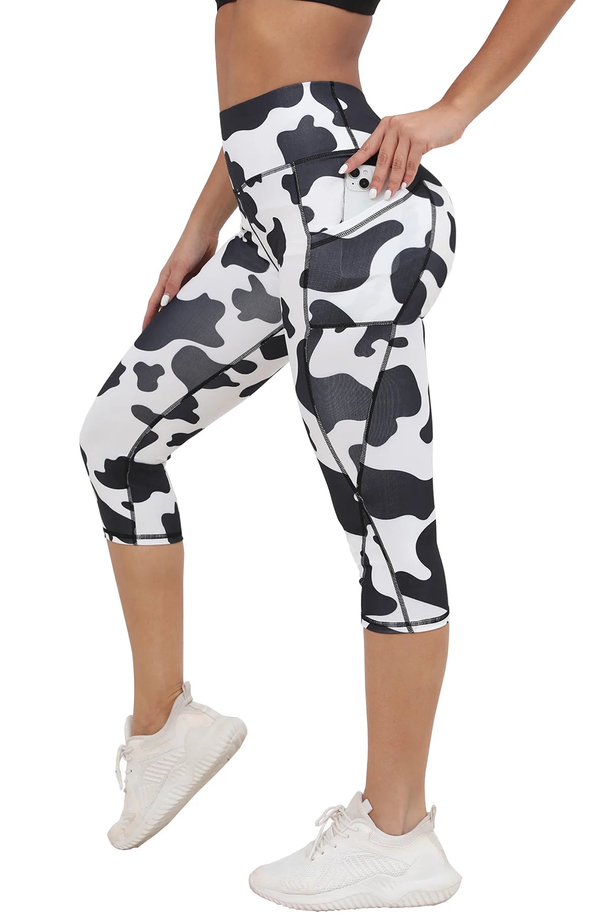 Women's Capri Yoga Pants with Pockets, high-waisted black and white cow print, stretchy athletic material, designed for workout.