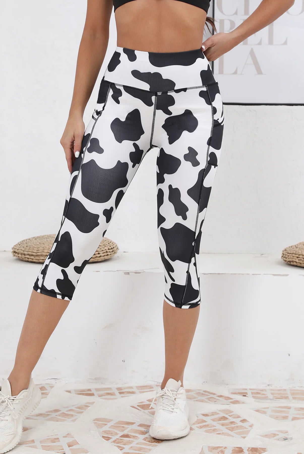 Women's Capri Yoga Pants with Pockets in black and white cow print, high-waisted, stretchy workout leggings with zipper details for active wear.