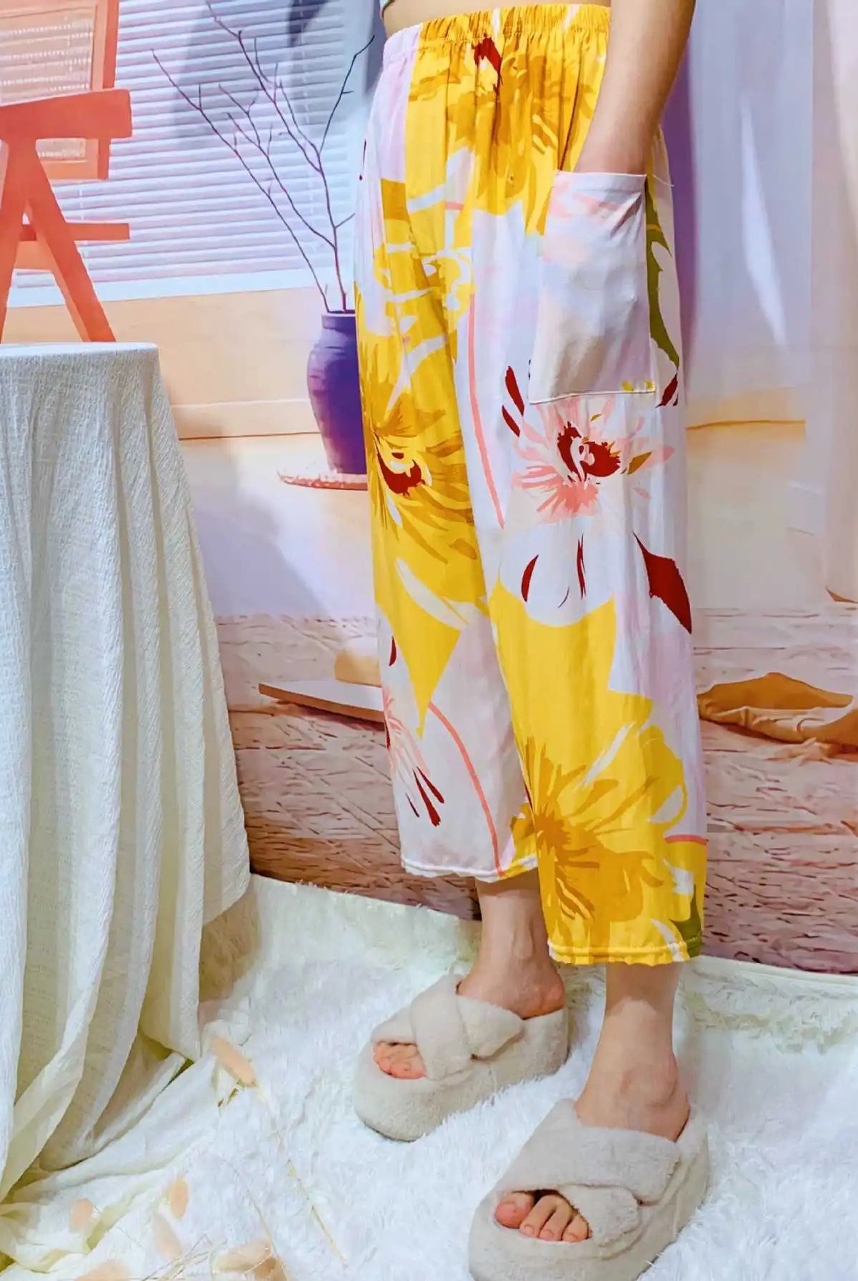 Yellow floral high-waisted wide leg cropped Capri pants with pockets, casual summer lounge wear, shown on a woman standing.