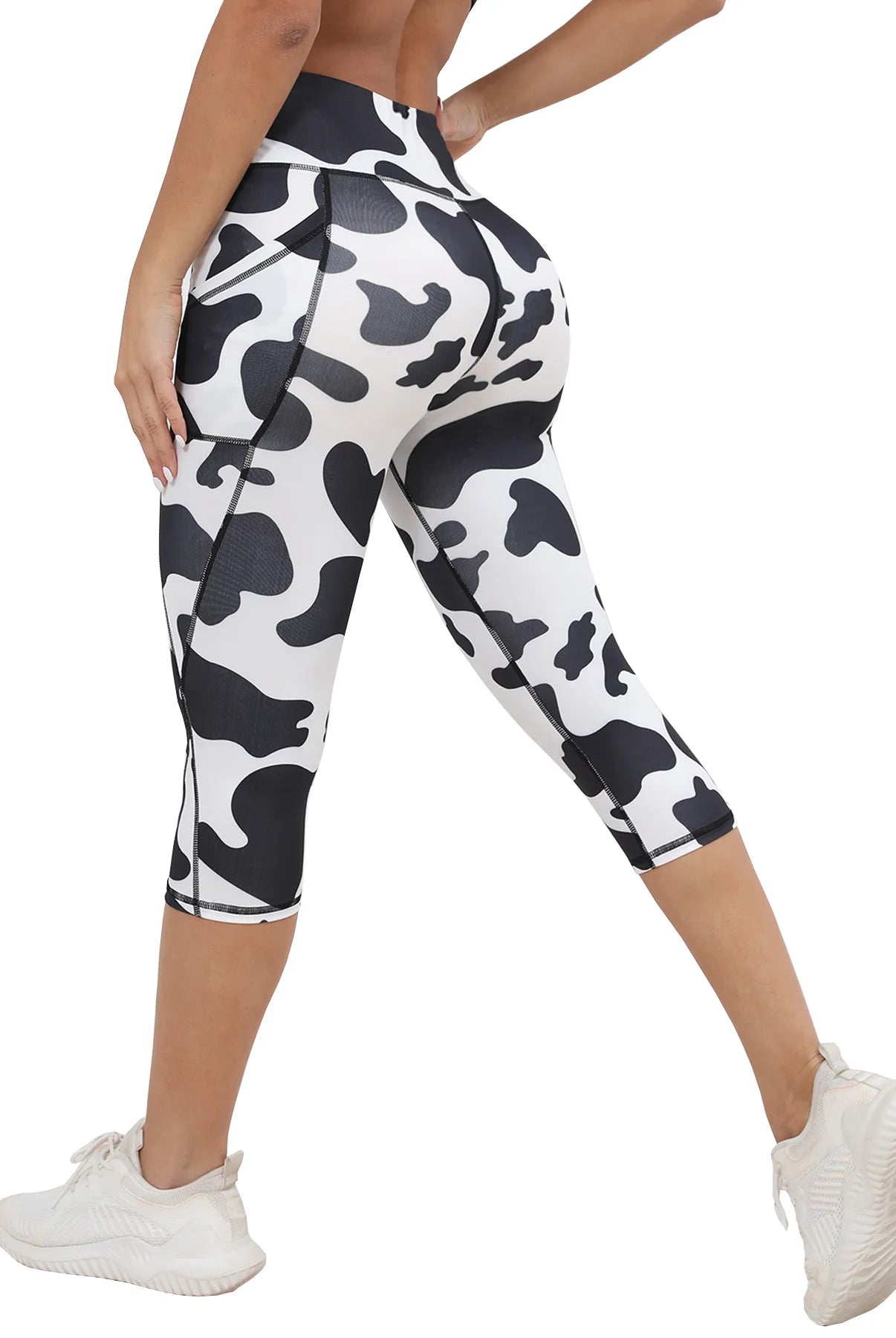 Women's Capri Yoga Pants with Pockets Essential High Waisted Legging for Workout in black and white cow print, stretchy athletic material.