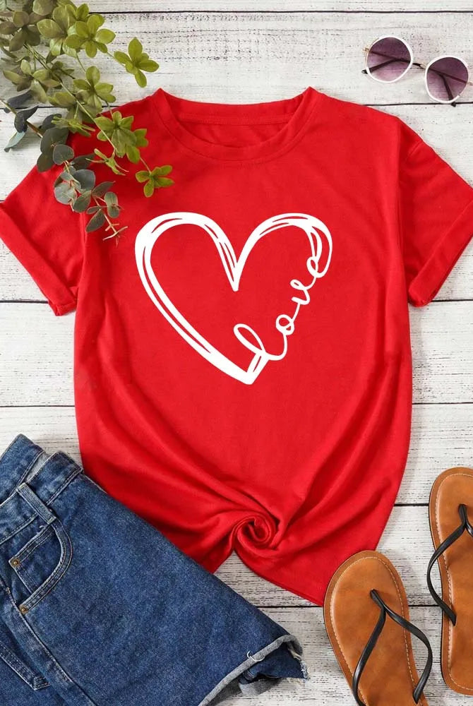 Love Heart Printed Trend Women Fashion Clothing Graphic T-shirt in red with white heart and love text, short sleeves, casual style, laid on wooden background with denim shorts, sunglasses, and sandals.