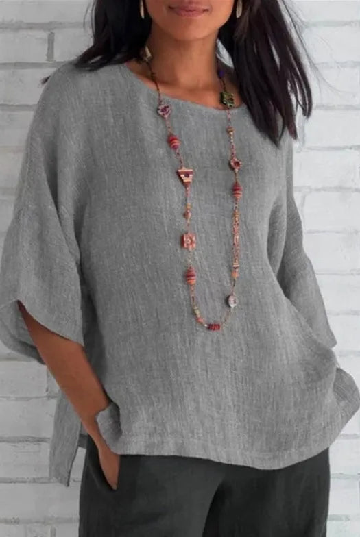 Plus Size Cotton Blouse Shirts Summer O-Neck Three Quarter Loose Casual Blouse Tops for Women worn with colorful beaded necklace against white brick wall.
