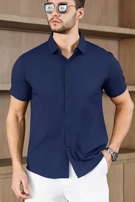 Men's business casual short-sleeved solid color shirt in navy blue, made of no-iron, comfortable fabric, worn by a male model indoors.
