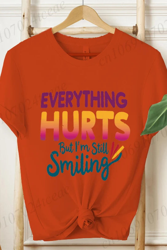 Everything Hurts But I'm Still Smiling Design Shirt, short sleeve orange tee with colorful text, casual summer fashion top.