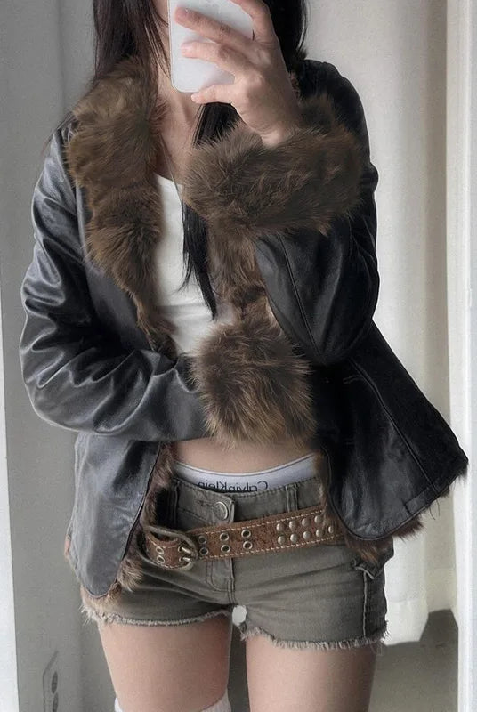 Faux Fur Patchwork PU Leather Jacket with furry collar, long sleeves, and thick winter outerwear design, styled with shorts and a belt.