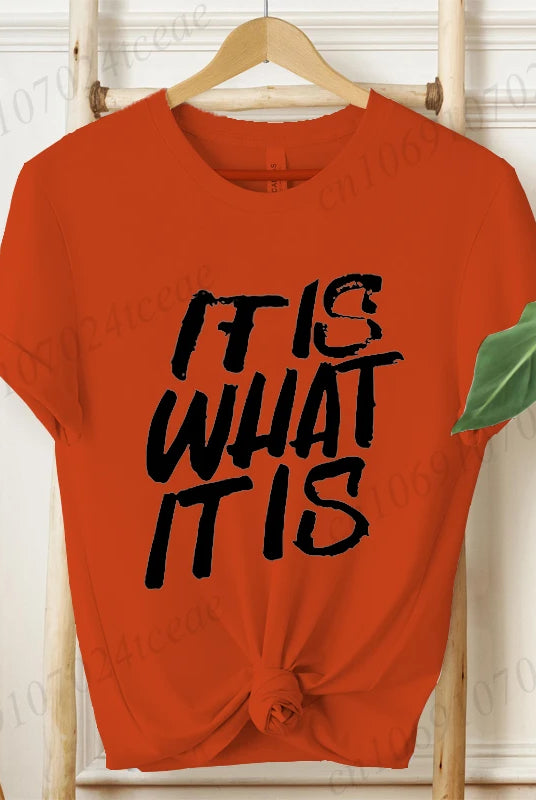 Red women's IT IS WHAT IT IS design shirt with bold black graphic text, short sleeves, and front knot, perfect for summer