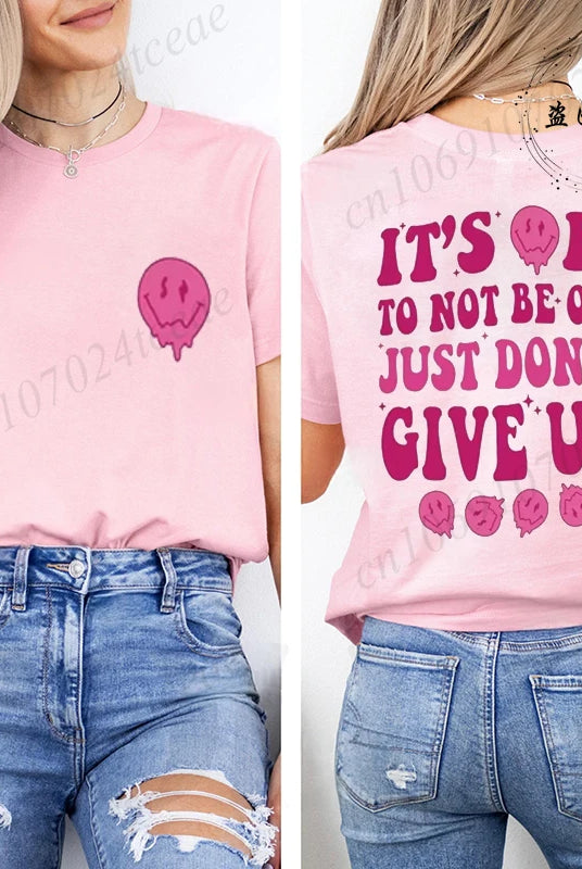 Pink casual summer T-shirt with It's OK to Not Be OK Just Don't Give Up slogan and smiling face graphic, worn with