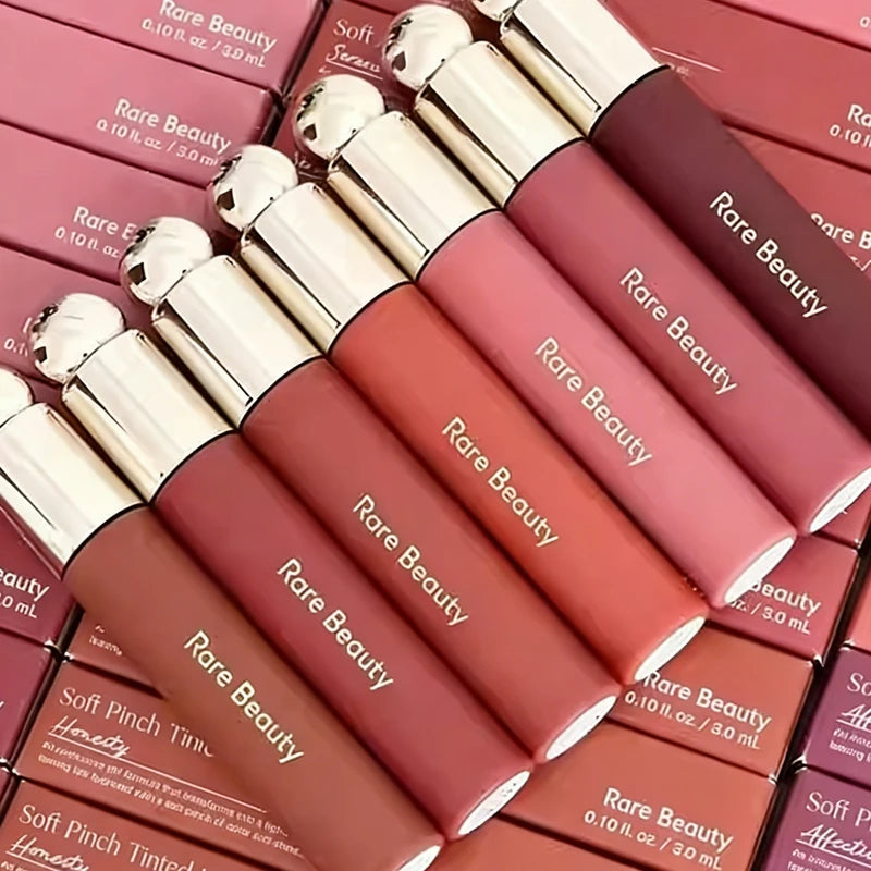 Rare Beauty 7-Colors Soft Pinch Tinted Lip Oil Stain Lip Gloss in pink and mauve shades with silver caps, displayed in boxes.