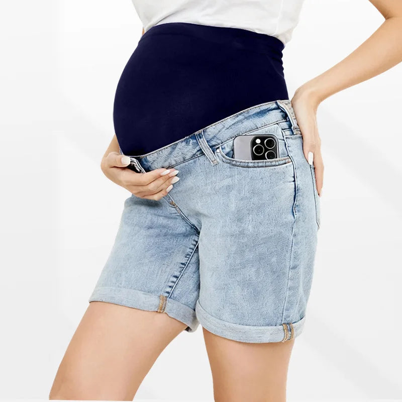 Pregnancy Capri Jeans High Waist Tummy Control Rolled Cuff Denim Shorts with a phone in the front pocket, worn by a pregnant woman.