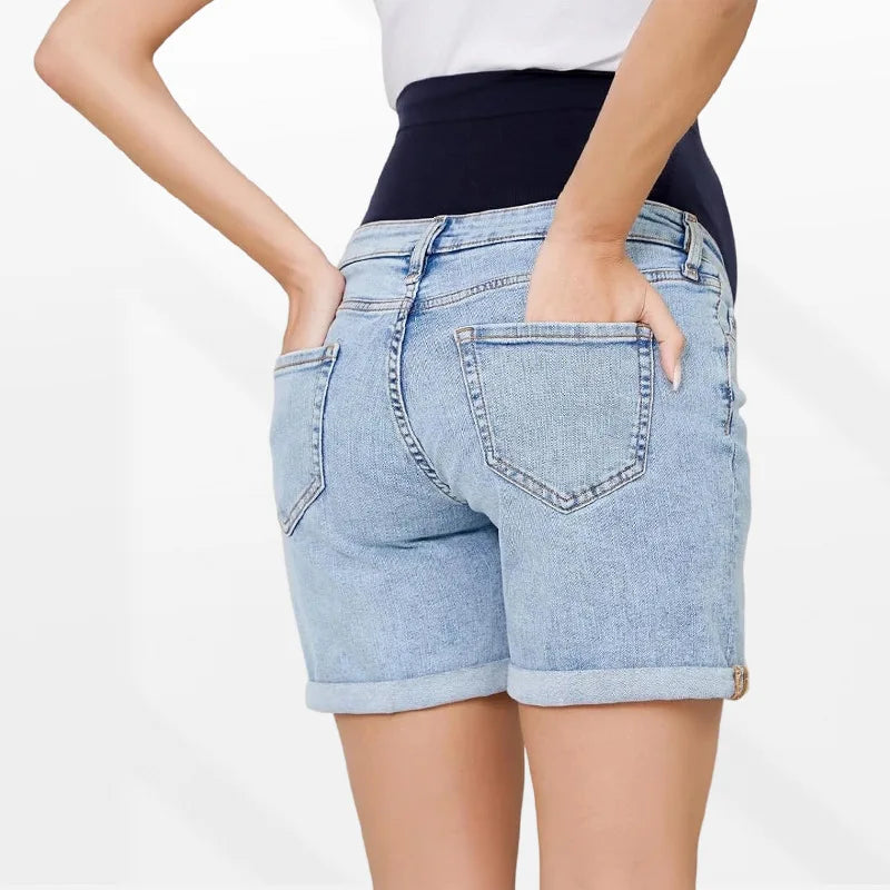 Pregnancy Capri Jeans High Waist Tummy Control Rolled Cuff Denim Shorts worn by a pregnant woman with hands in back pockets, light blue denim with rolled cuffs.