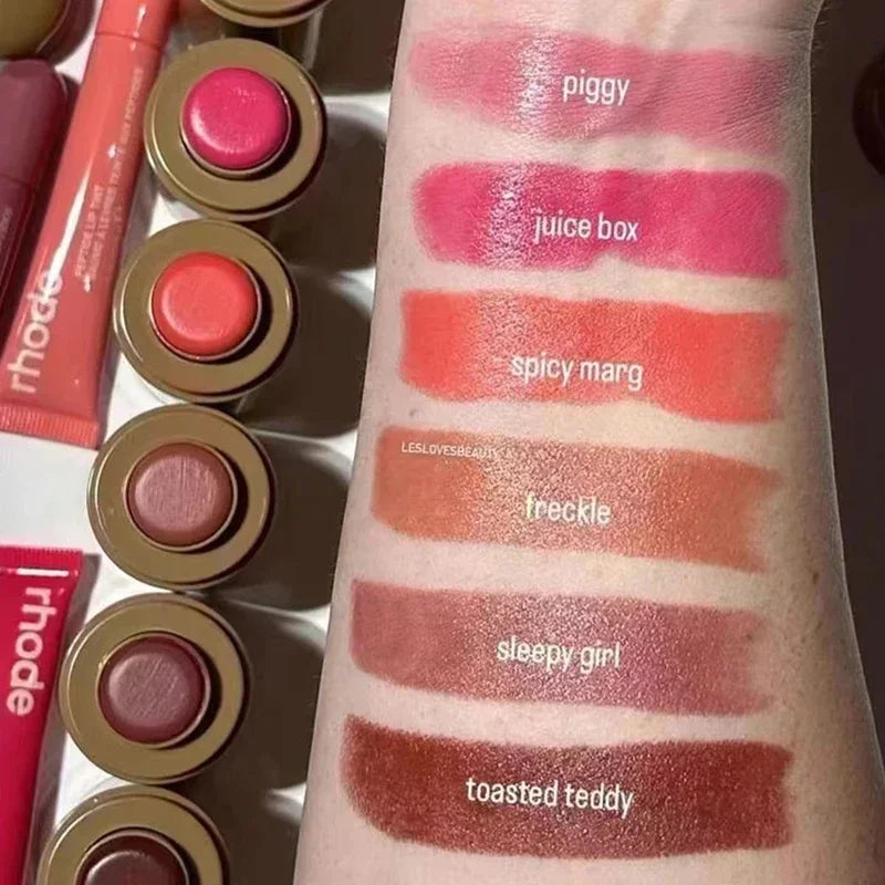 Swatch of Brand skin Balm Jelly Bean Lip Gloss in shades Piggy, Juice Box, Spicy Marg, and others on arm, showing vibrant