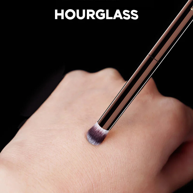 Hourglass Makeup Brushes Powder Foundation Concealer Blusher Bronzer Eye Shadow Eyebrow Eyeliner Sculpting Brush with rose gold handle and synthetic bristles on hand.