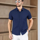 Men's business casual short-sleeved solid color shirt in navy blue, made of no-iron, comfortable fabric, worn by a male model indoors.