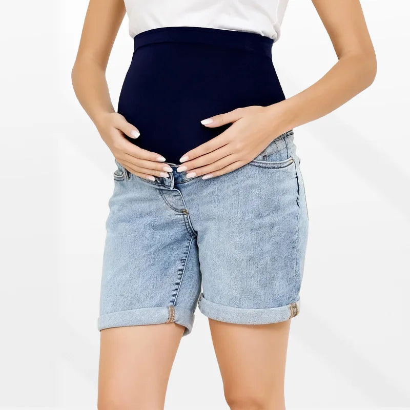 Pregnancy Capri Jeans High Waist Tummy Control Rolled Cuff Denim Shorts worn by a pregnant woman, featuring dark blue high-waist maternity jeans with rolled cuffs.