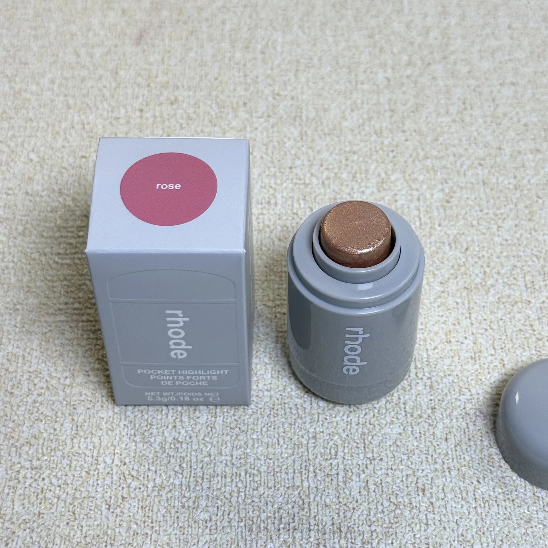 Rhode Highlight Stick with four brightening colors: Pearl, Rose, Sunlight, and Bronzo, in a sleek gray tube with a beige