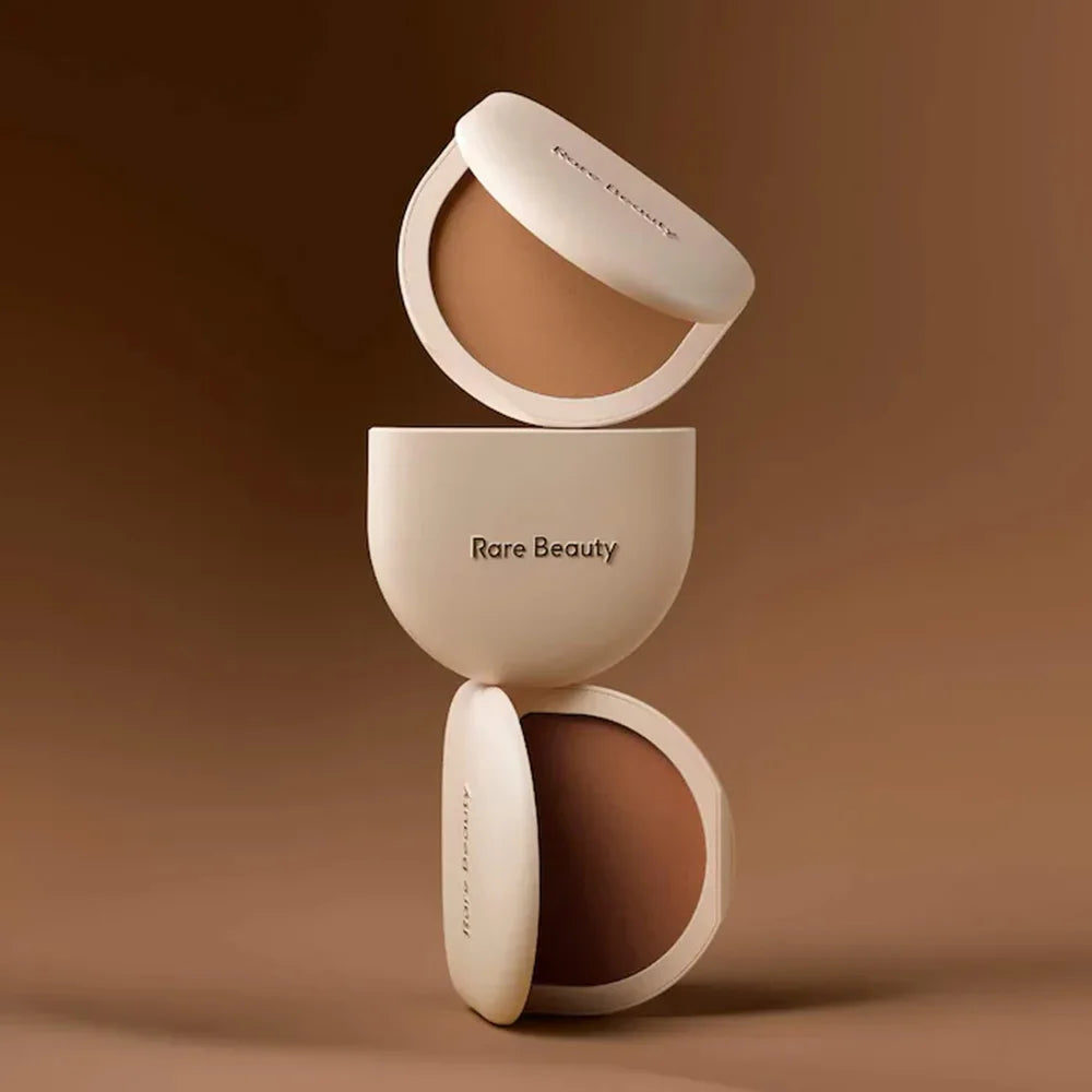 Rare Beauty Stay Genuine Shaded Compact Setting Powder in beige and brown shades, stacked with open lids showing pressed